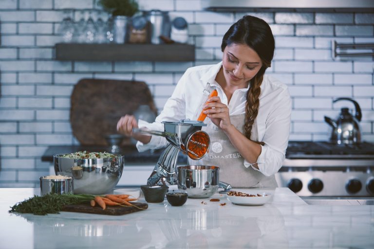 Saladmaster consultant grating carrots with a food processor, showcasing healthy cooking and non-toxic cookware.