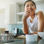Healthy woman with Saladmaster pot, leaning on kitchen benchtop, ready for a non-toxic cookware demonstration.