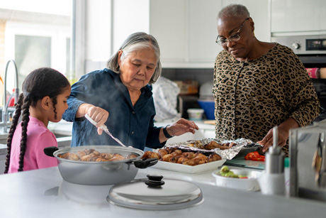 Elderly women serving healthy Saladmaster meals to a young girl using waterless cooking and non-toxic cookware techniques.
